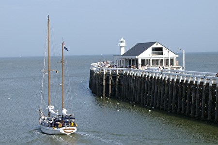 een zeilboot passeert langs het oosterstaketsel met witte brasserie