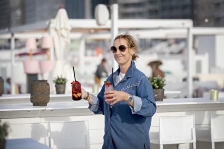 dame draagt 2 cocktails in het witte interieur van een strandbar