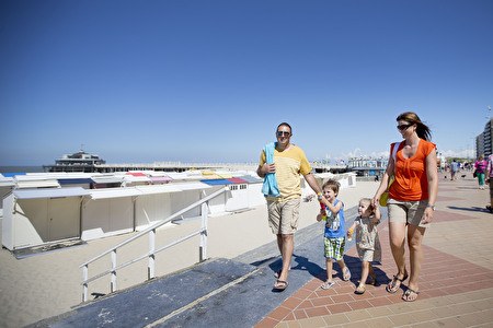 zomers gezin met kindjes wandelt langs de zeedijk