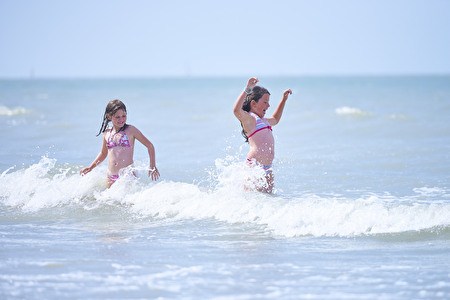 Twee meisjes spelen in de branding van de zee