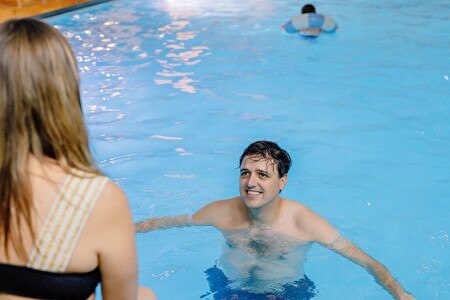 man in het water met vrouw op de badrand