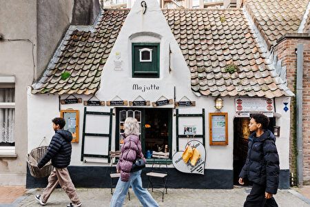 historisch wit vissershuisje met lage ramen en rode dakpannen